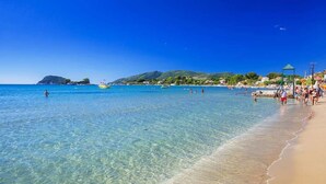 A beach with clear water, a sandy shore, and a few people.