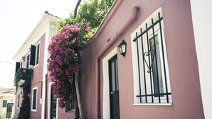 A building with a pink facade, black window bars, and a black door.