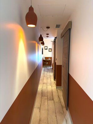 A hallway with a tiled floor, pendant lighting, and a door on the right.