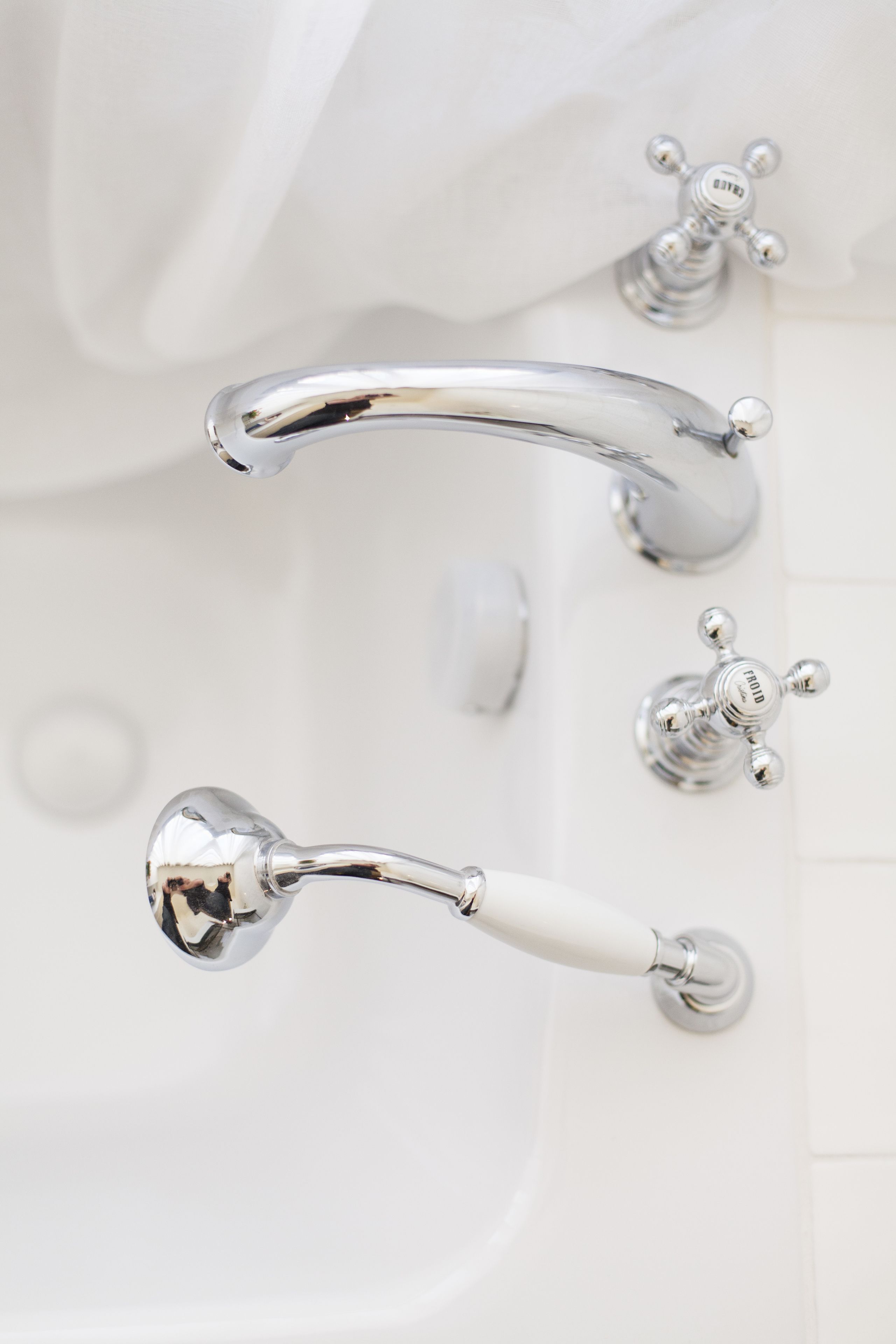 A bathroom with a white bathtub, a chrome faucet, and a white handheld showerhead.