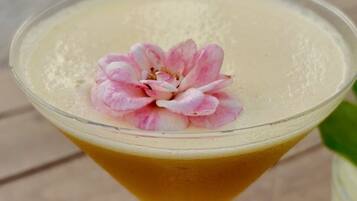 Un verre à martini orné d’une fleur rose, posé sur une table.