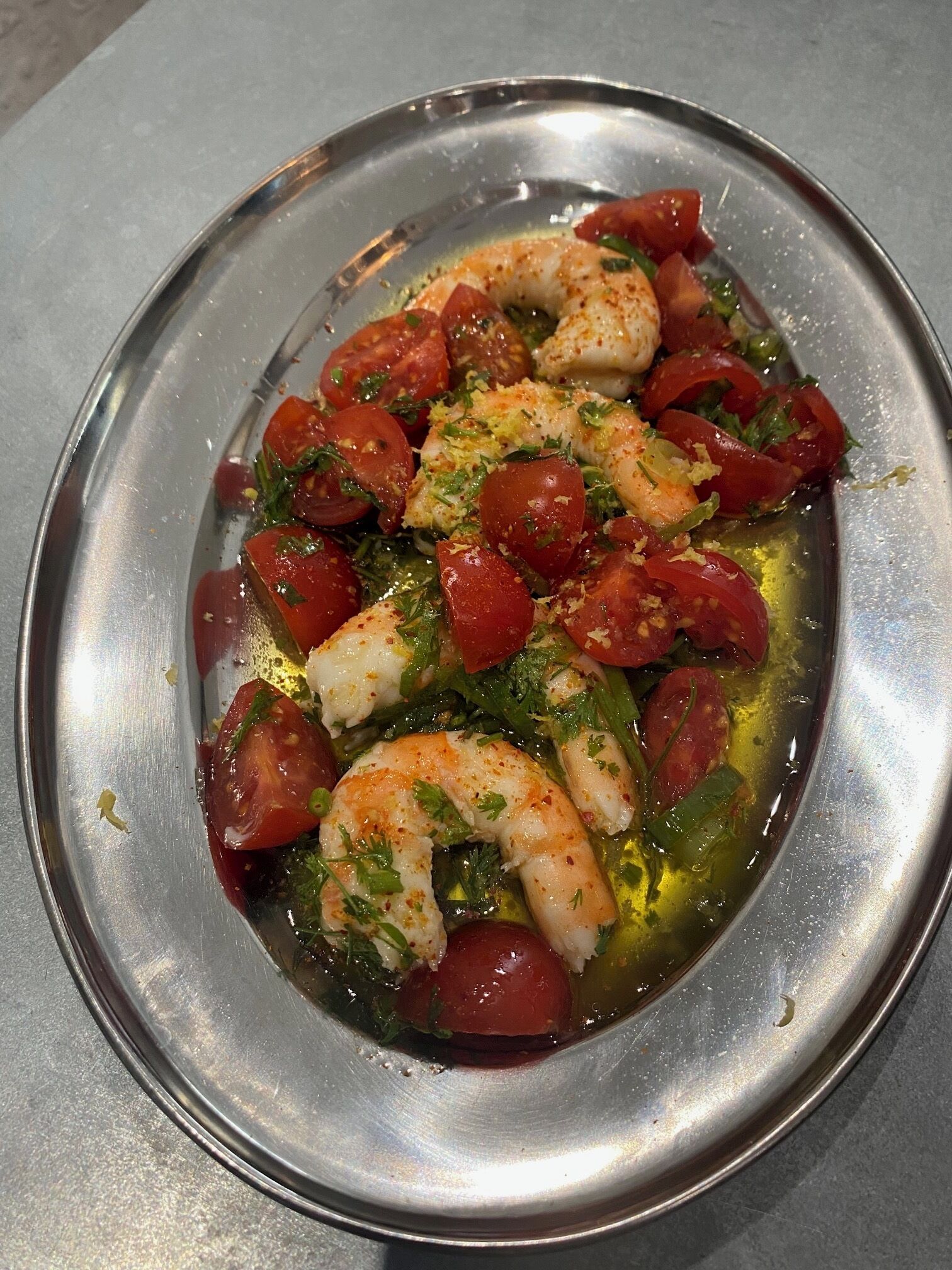 A plate of seafood with tomatoes and herbs.