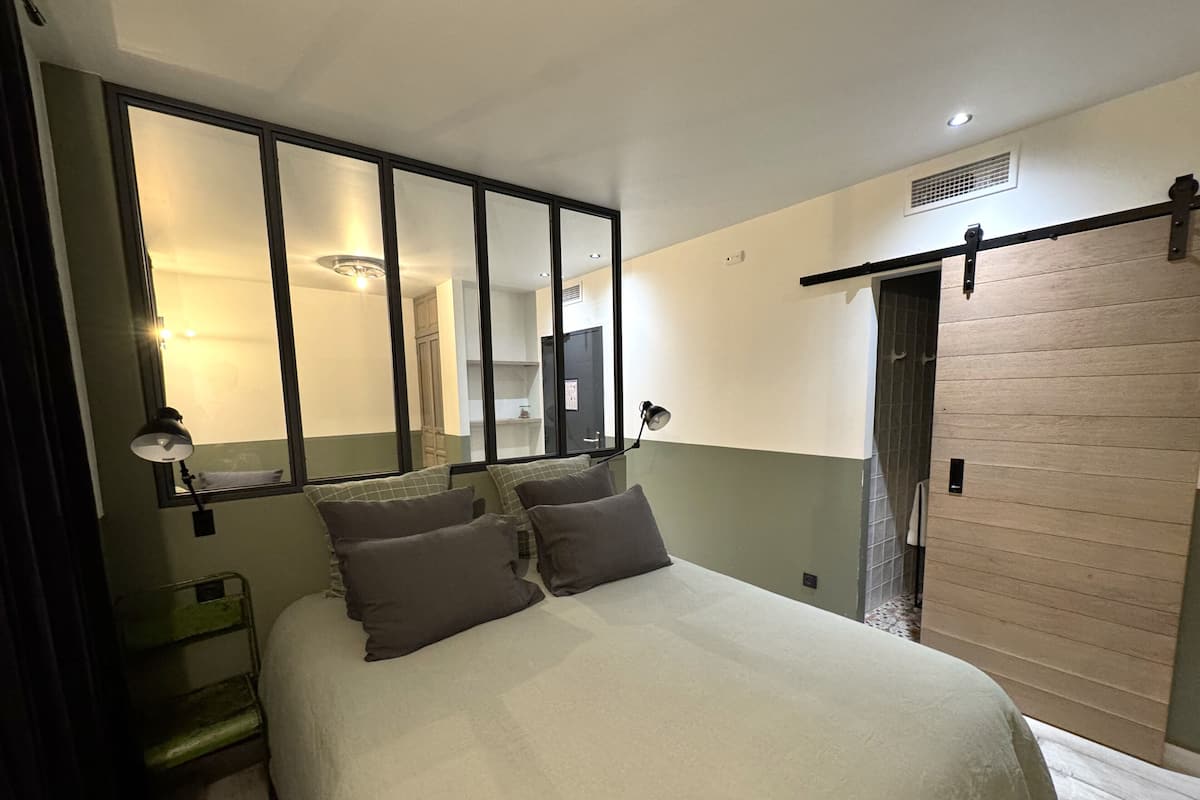 Un dormitorio con una cama grande, dos lámparas de noche, un espejo y una puerta corrediza.