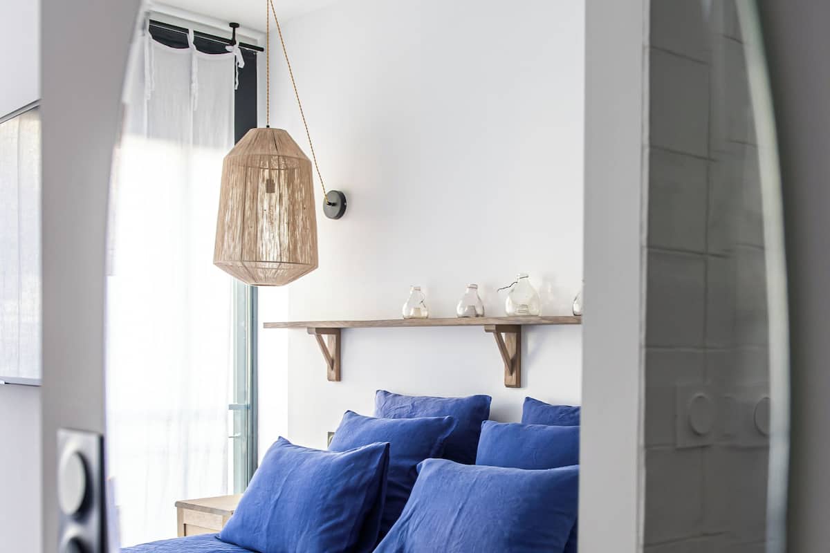 Un dormitorio con cama, lámpara colgante y ventana con cortinas.