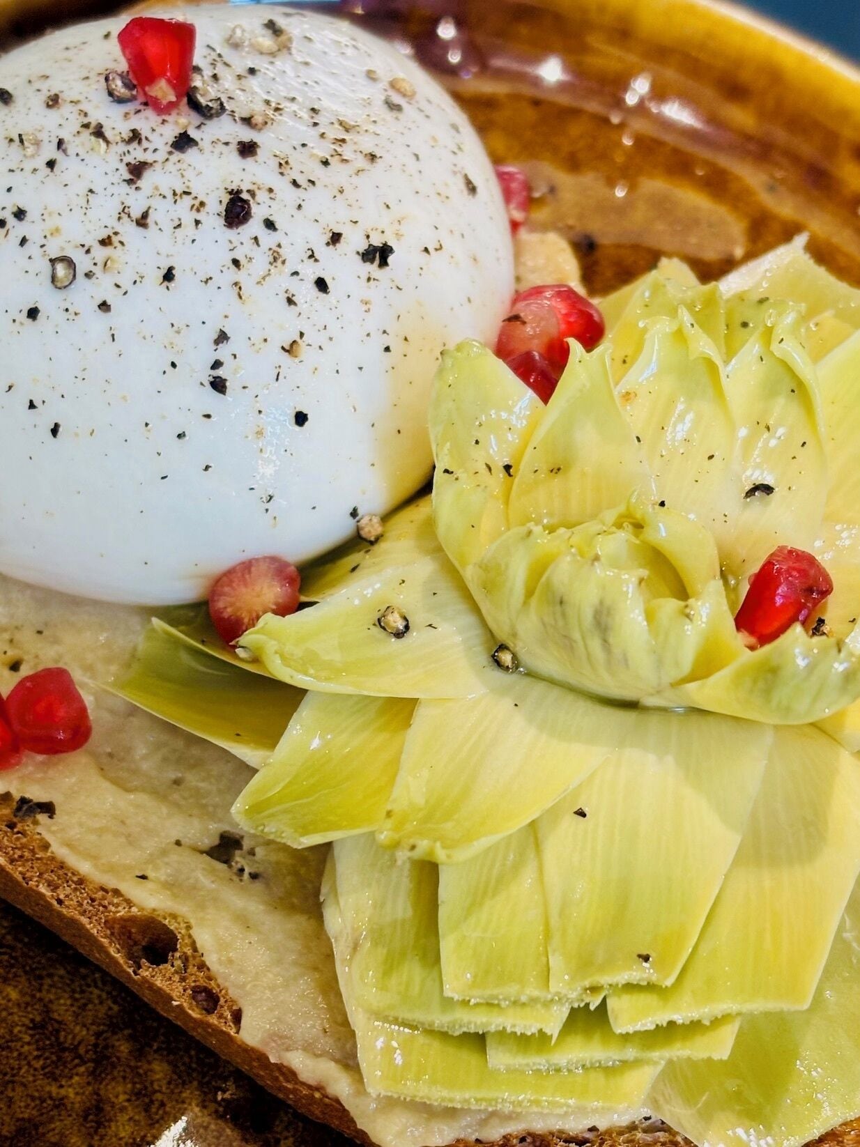A plate with a poached egg, artichoke hearts, and pomegranate seeds.