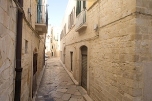 A narrow cobblestone street flanked by historic stone buildings with arched doorways and balconies. - B&B Suite Paciotti (Trani)