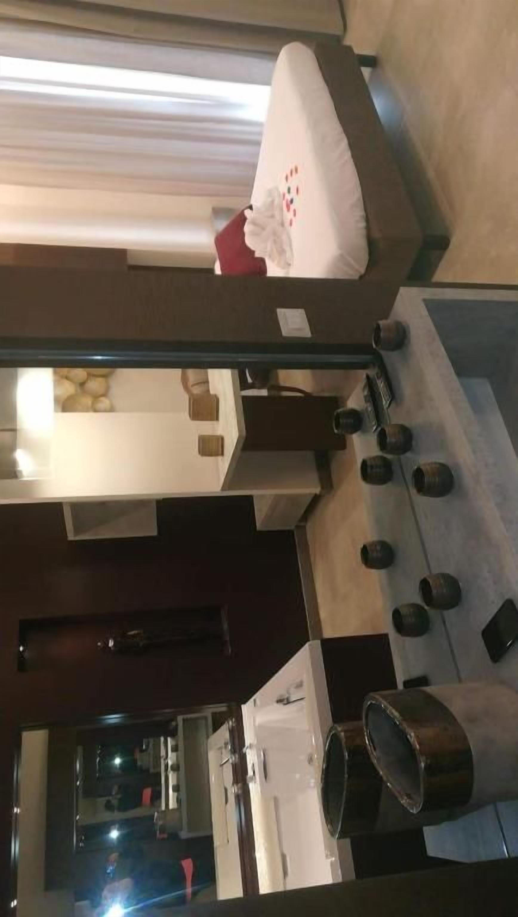 A room with a bed, a small table, and a mirror. There are several round objects on the floor, possibly for decoration or storage.