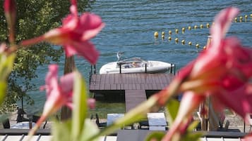 A boat docked at a lakeside restaurant with outdoor seating and a view of the water.