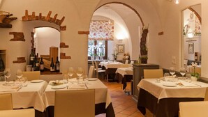 A restaurant with tables set for dining, brick walls, and a floral window display.