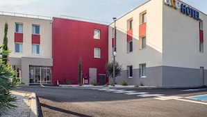Un hôtel moderne avec une façade rouge et beige, de nombreuses fenêtres et une entrée bien visible.