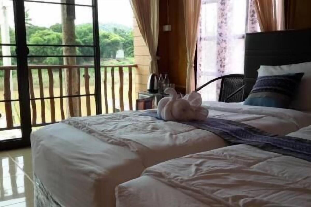 Una cama con una colcha blanca, un almohadón mullido y un cojín decorativo.