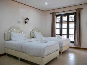 Habitación de hotel con dos camas, una lámpara fijada a la pared y un ventanal con cortinas.