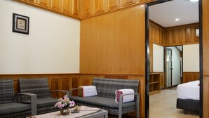 Habitación de hotel con pared de madera, un sofá, una mesita con un jarrón de flores y una cama.