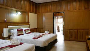 Habitación de hotel con dos camas, paneles de madera, una mesita de noche con lámpara y vistas al exterior.