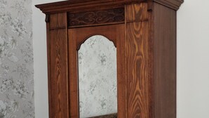 A wooden wardrobe with a mirror, a bed with white bedding, and a floral wallpaper pattern. - Cragowlet House East (Helensburgh)
