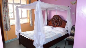 A bed with a canopy, a chair, and a window with curtains. - Hotel Southern Blue (Nairobi)