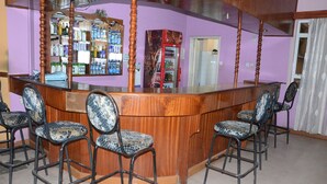 A bar area with a wooden counter, bar stools, and a refrigerator. - Hotel Southern Blue (Nairobi)