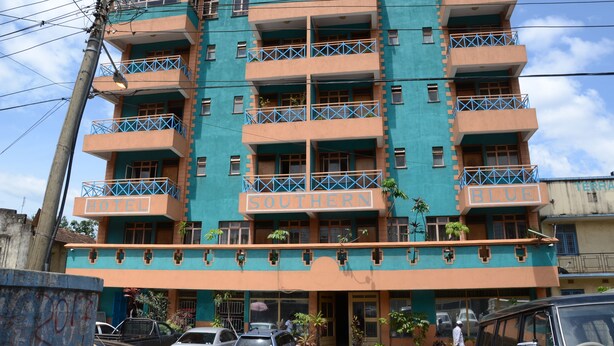 A multi-story hotel with balconies, a sign indicating it is a hotel, and several parked cars in front. - Hotel Southern Blue (Nairobi)