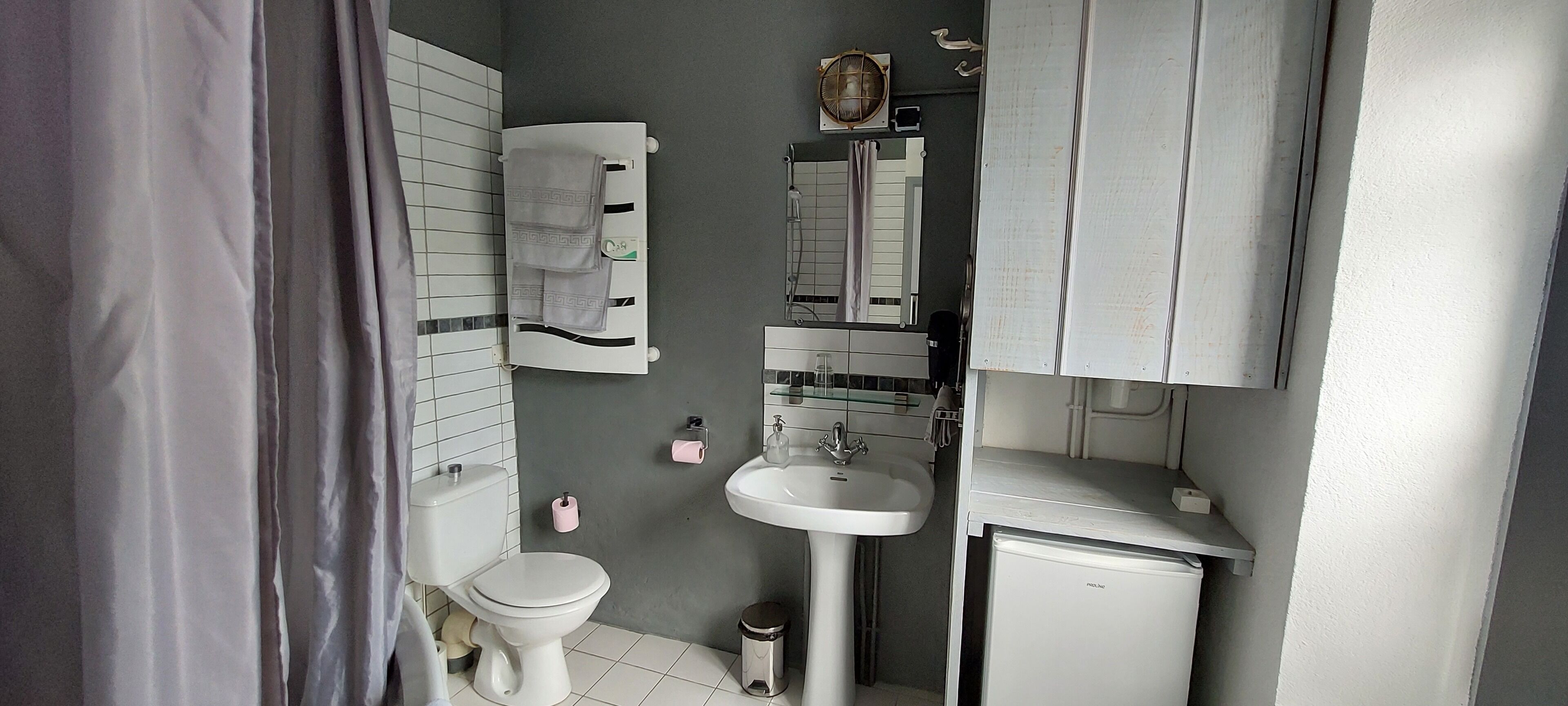 A compact bathroom with a toilet, sink, and towel rack.