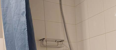 A shower area with a handheld showerhead, a wall-mounted faucet, and a soap dispenser.