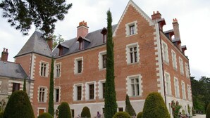 A large, historic building with a symmetrical facade, multiple chimneys, and a well-maintained garden with neatly trimmed hedges. - La Source de Bury (Valencisse)