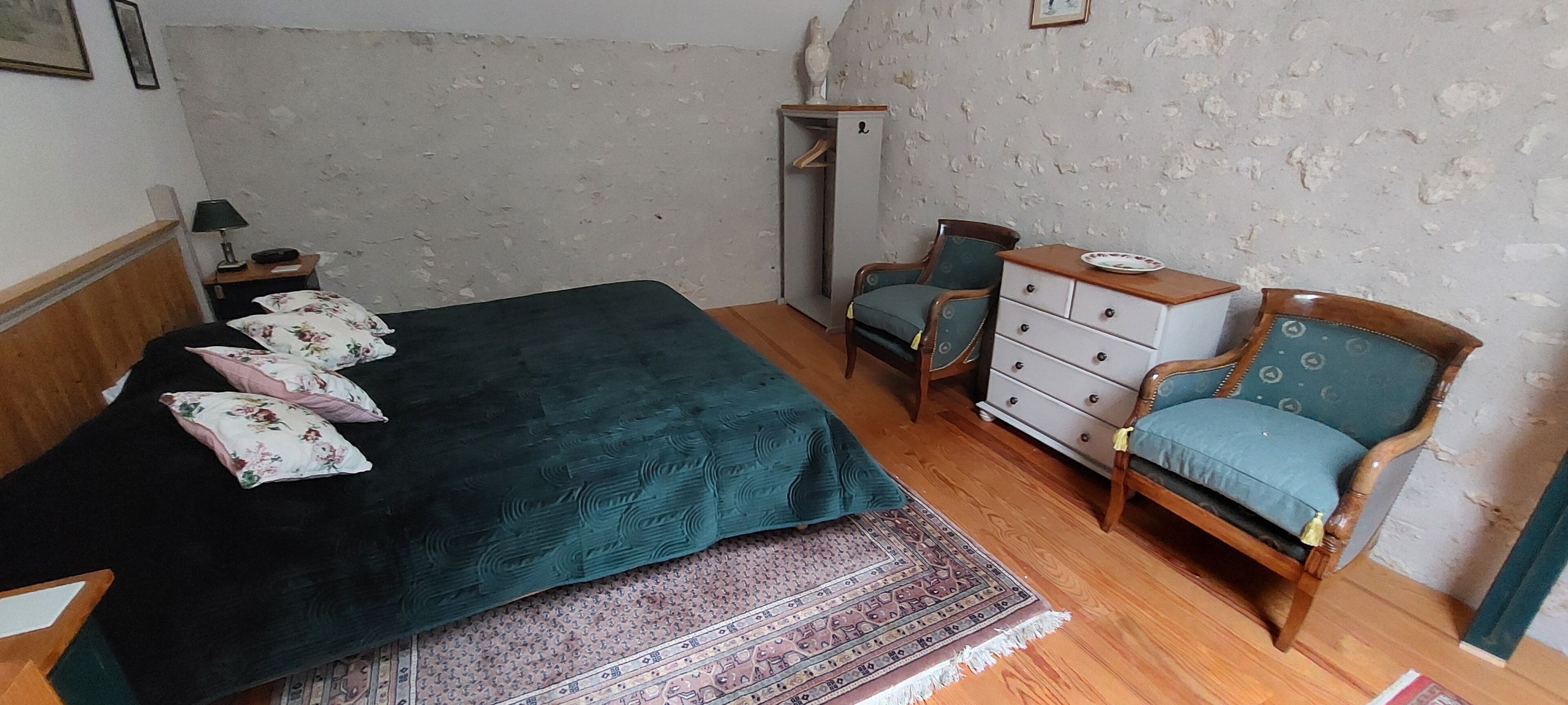 A bedroom with a bed, a chair, a dresser, and a nightstand.
