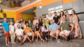 Un grupo de personas en una cocina moderna con armarios grises, paredes anaranjadas y un reloj visible.