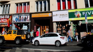Un edificio de varios pisos con diversas tiendas en la planta baja, incluyendo una pizzería y una tienda de muebles.