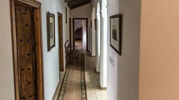 A hallway with wooden doors, patterned rugs, and framed pictures on the walls.