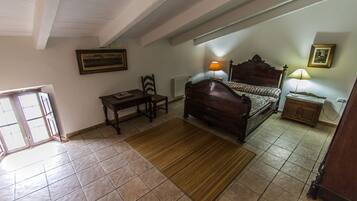 Un dormitorio con cama de madera, mesita de noche, silla, escritorio y radiador.