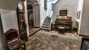 A spacious hallway with a grand piano, a wooden chair, and a clock on the wall. - Finca Villa Juan (Ribera del Fresno)