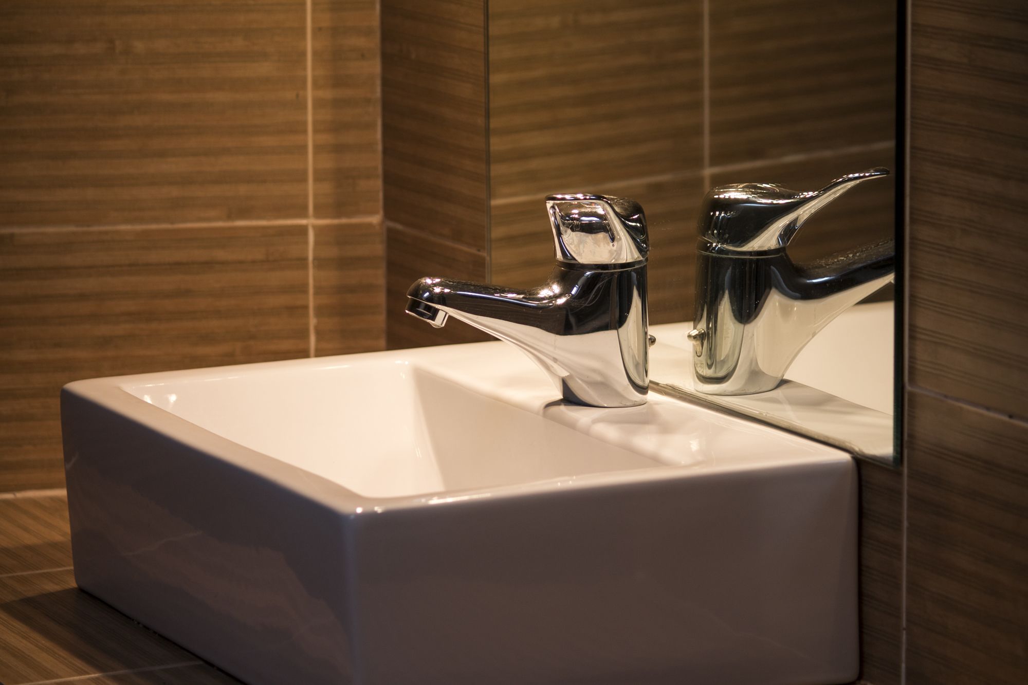 A modern bathroom with a chrome faucet and a white sink.