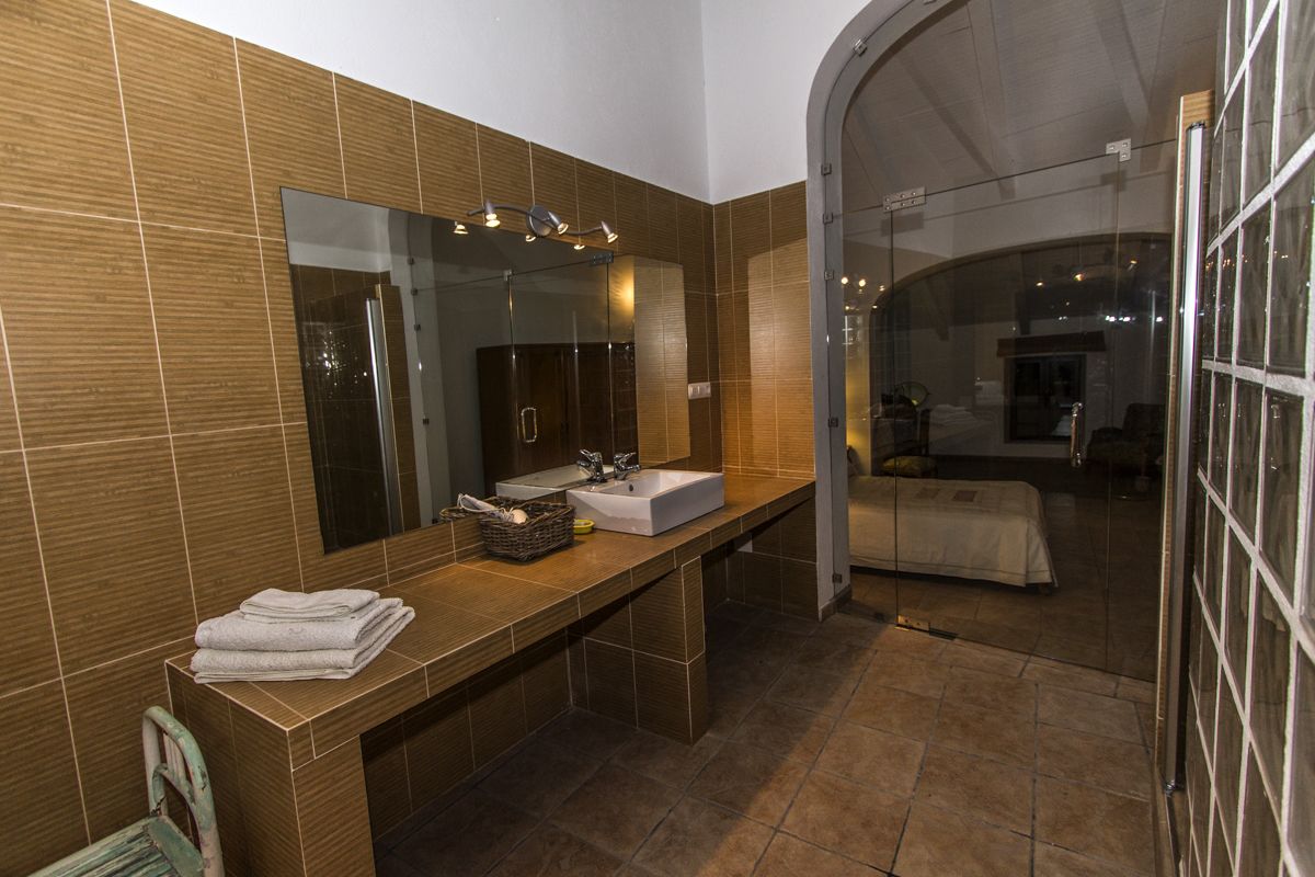 A modern bathroom with a large mirror, two sinks, and a glass-enclosed shower area.