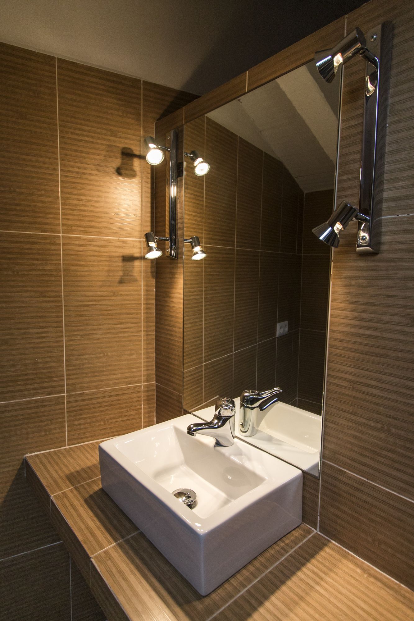 Un baño moderno con un espejo grande, dos lavamanos e iluminación en el techo.