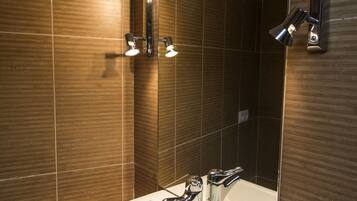 Un baño moderno con un espejo grande, dos lavamanos e iluminación en el techo.