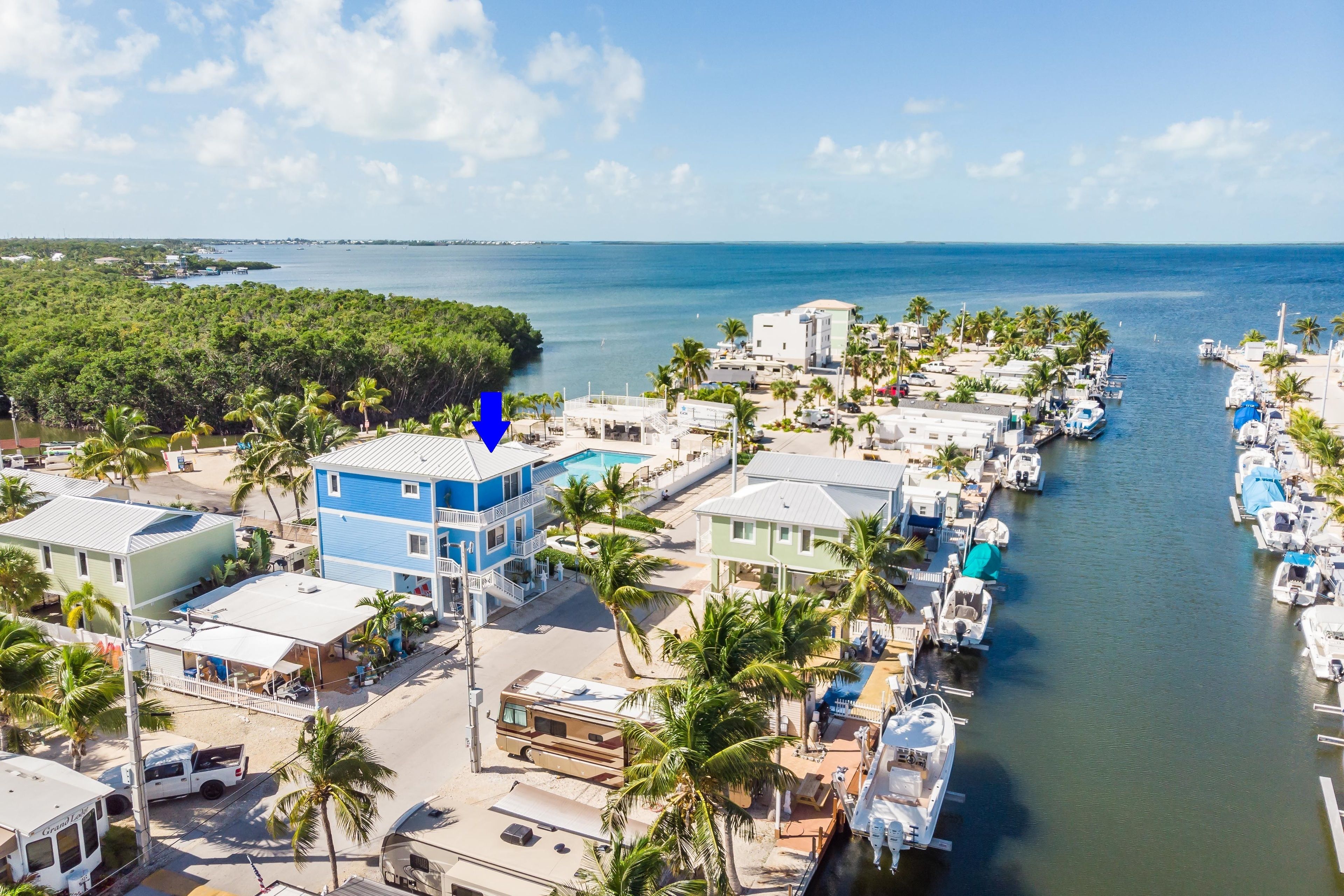 Un puerto deportivo con barcos amarrados, rodeado de edificios residenciales y palmeras.