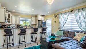 A kitchen with bar stools, a coffee machine, and a refrigerator. - Brand New Key Largo Home (Key Largo)