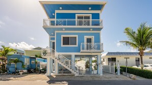 A two-story building with a balcony on the upper floor, a staircase leading to the entrance, and a small porch area. - Brand New Key Largo Home (Key Largo)