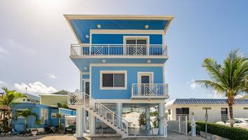 A two-story building with a balcony on the upper floor, a staircase leading to the entrance, and a small porch area.