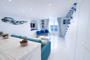 A modern living room with a sofa, chairs, a dining table, and a kitchen area. - La Terrazza De Luxe (Sorrento)