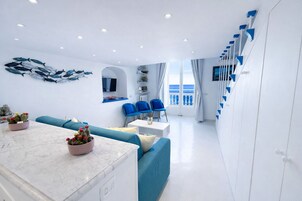 A modern living room with a sofa, chairs, a dining table, and a kitchen area.