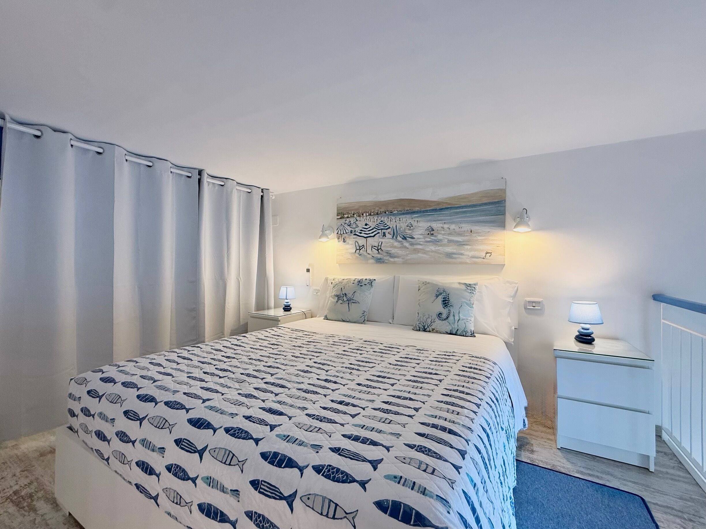 Une chambre à coucher avec un lit, un tableau, deux lampes de chevet et une table de nuit.