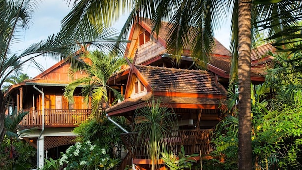 A wooden house with multiple levels, surrounded by lush tropical vegetation. - Golden Teak Home Resort (Chiang Mai)