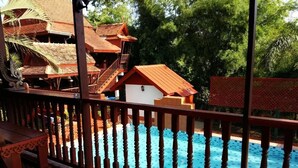 A wooden deck with a pool, surrounded by traditional wooden buildings with red roofs. - Golden Teak Home Resort (Chiang Mai)