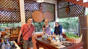 A kitchen with a wooden table, bottles, and a refrigerator. - Golden Teak Home Resort (Chiang Mai)