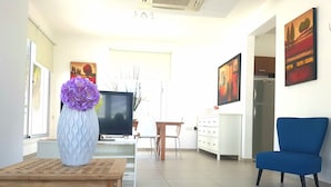 Ein modernes Wohnzimmer mit Fernseher, einem blauen Sessel und Kunstwerken an den Wänden.