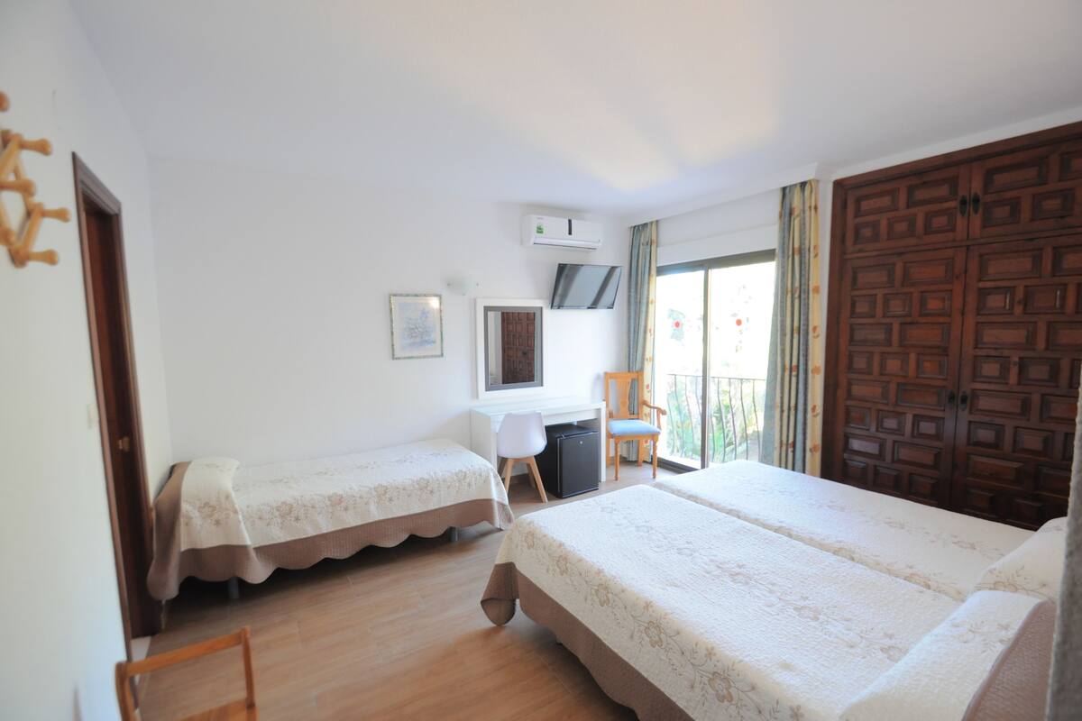 Una habitación con dos camas, un escritorio, una silla y un armario.