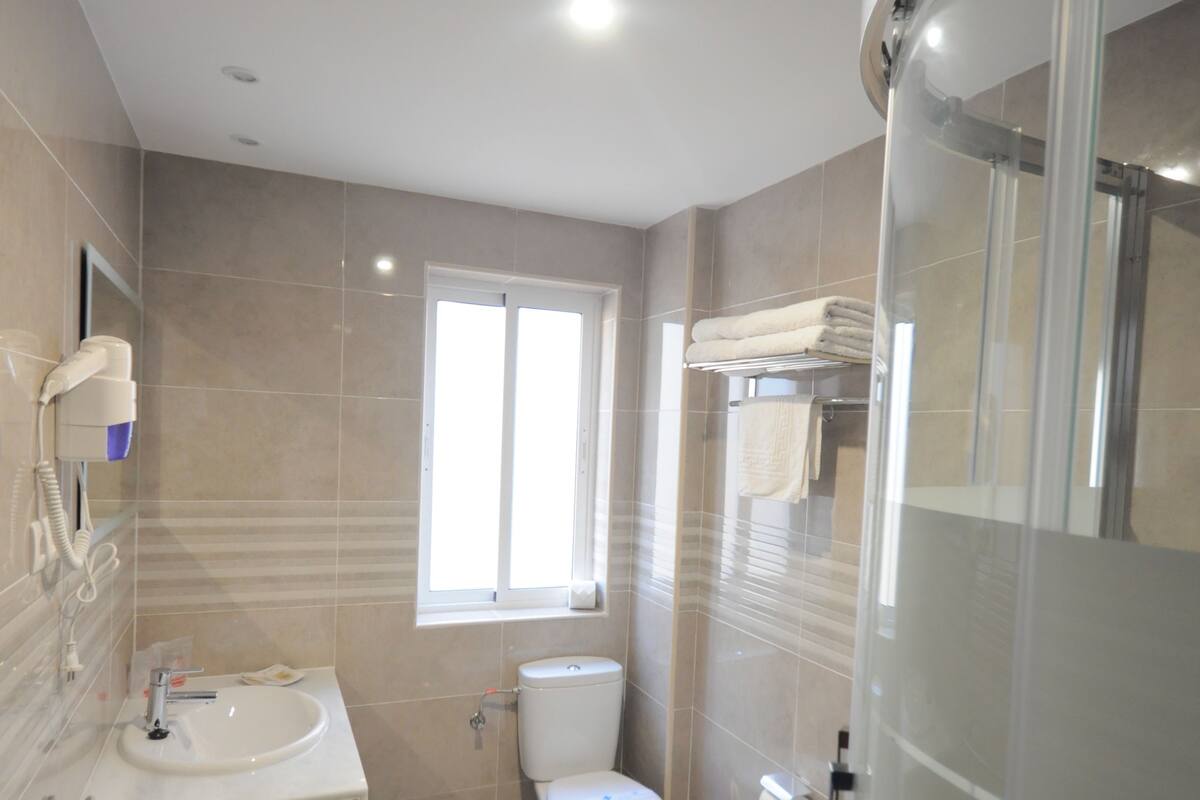 Un baño moderno con lavamanos, inodoro y zona de ducha.
