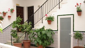 Un patio con plantas en macetas, una escalera y una puerta.
