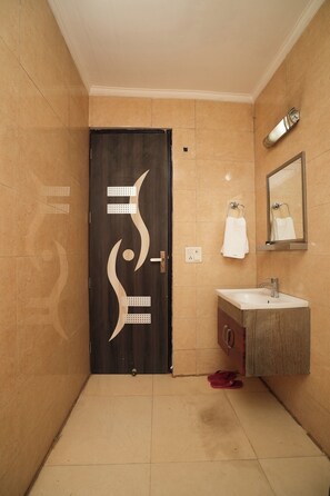 A bathroom with a dark door, a white sink, and a mirror. - Kabul Hotel Medanta Hospital, Gurugram (Gurugram)